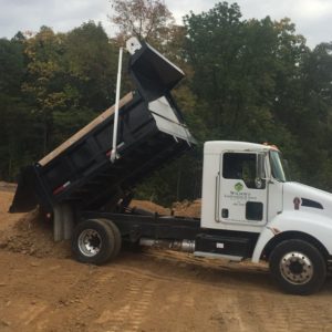 A dump truck is parked on the dirt.